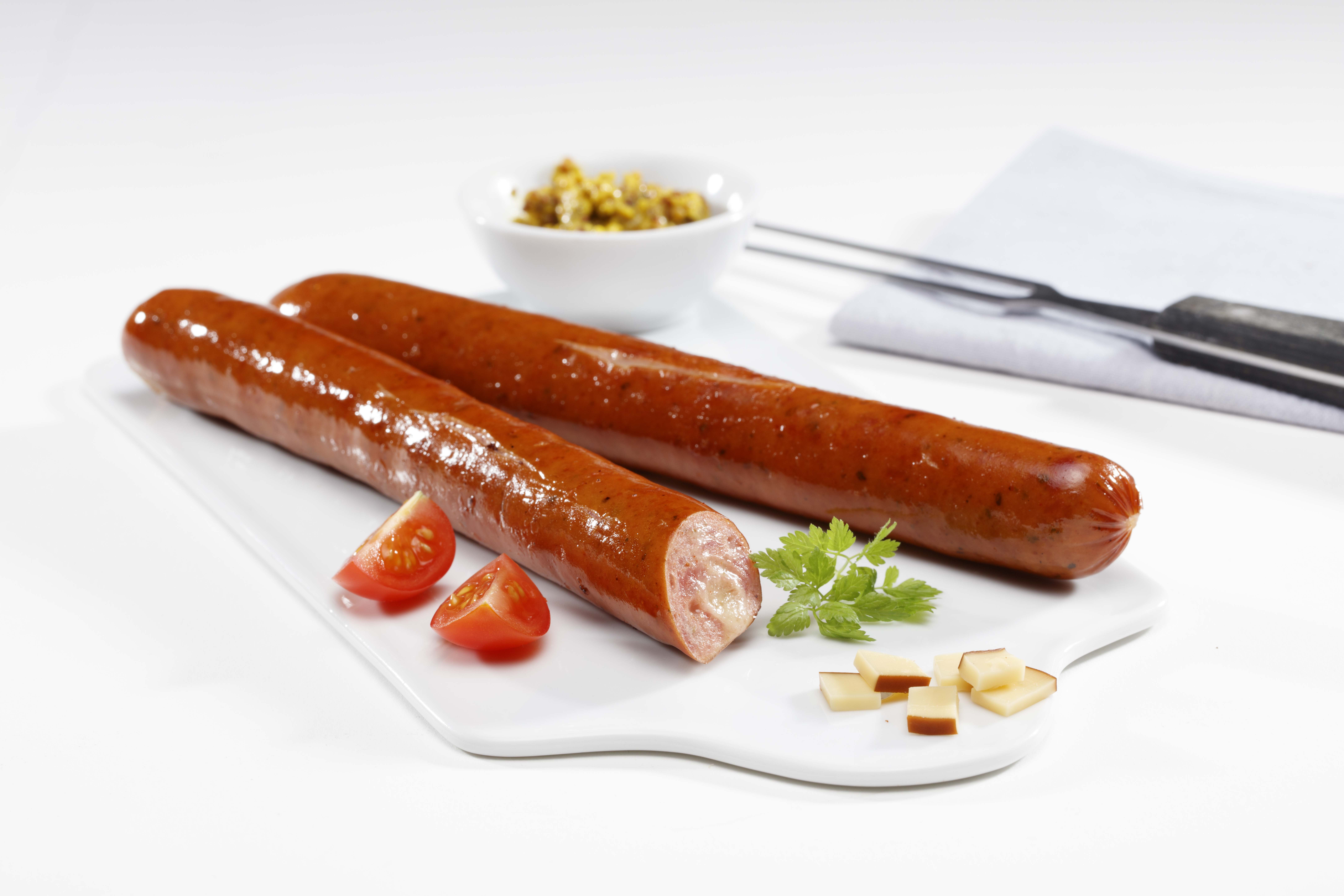 Zwei schlanke Krakauer mit Käse und Gewürzen auf einem Teller. Ein Würstchen ist im Anschnitt zu sehen.