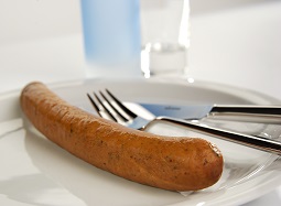 Eine Krakauer auf einem Teller mit Besteck.