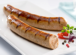 Zwei gebratene Bratwürstchen mit Gewürzen auf einem Teller. Ein Würstchen ist im Anschnitt zu sehen.