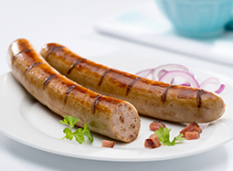 Zwei gebratene Bratwürstchen mit Gewürzen auf einem Teller. Ein Würstchen ist im Anschnitt zu sehen.