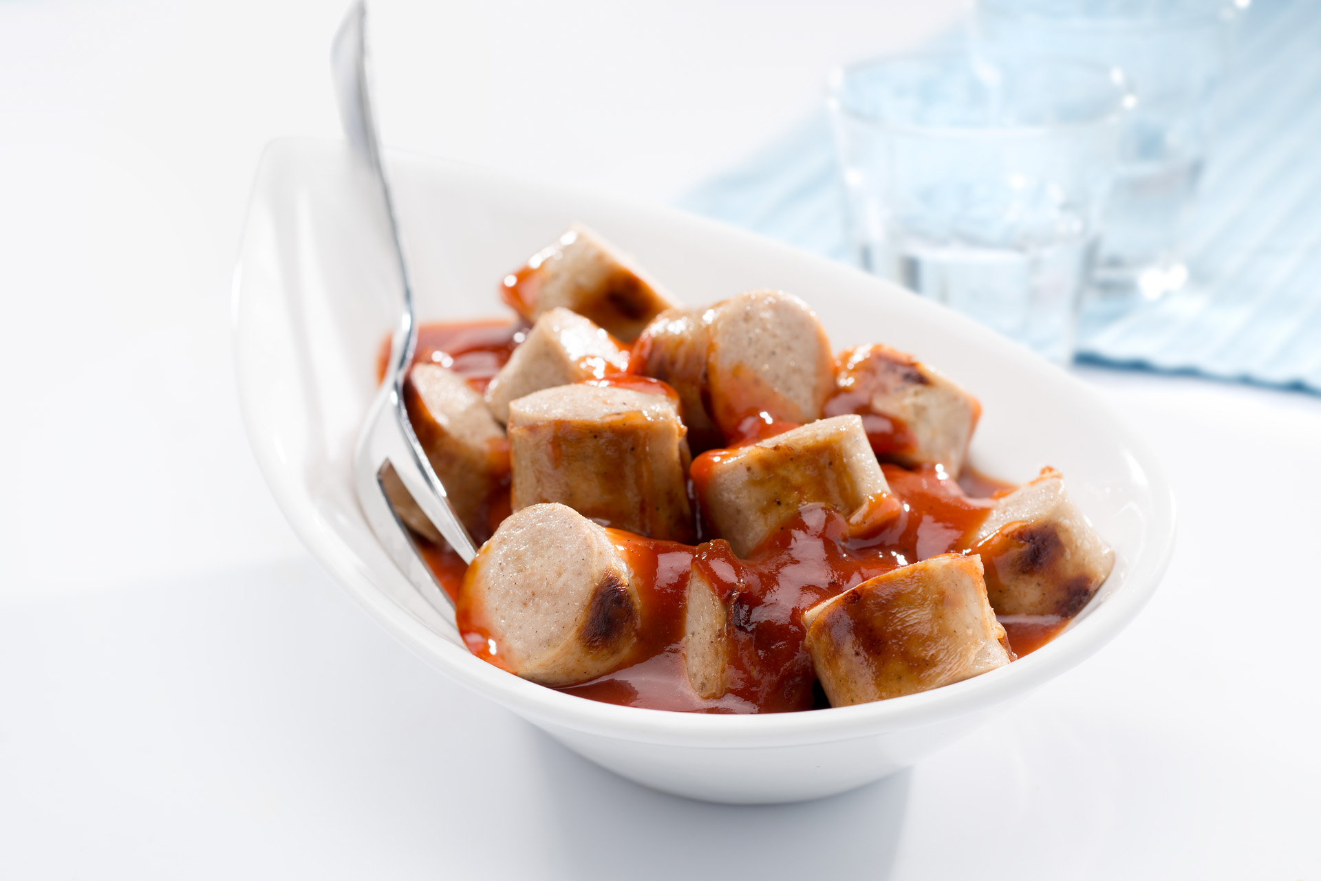 Gebratene und geschnittene Bratwurst mit Currysauce in einer Schale