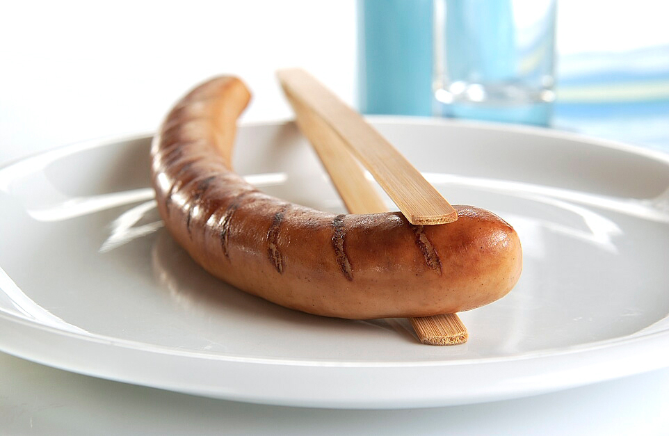 Eine gebratene Bratwurst auf einem Teller.