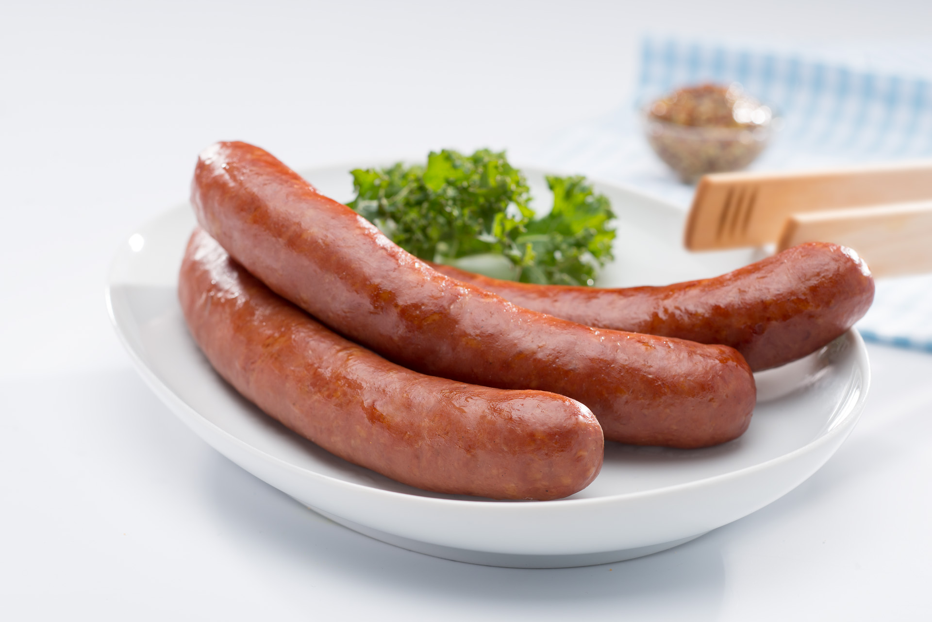 Drei Mettwürstchen auf einem Teller.