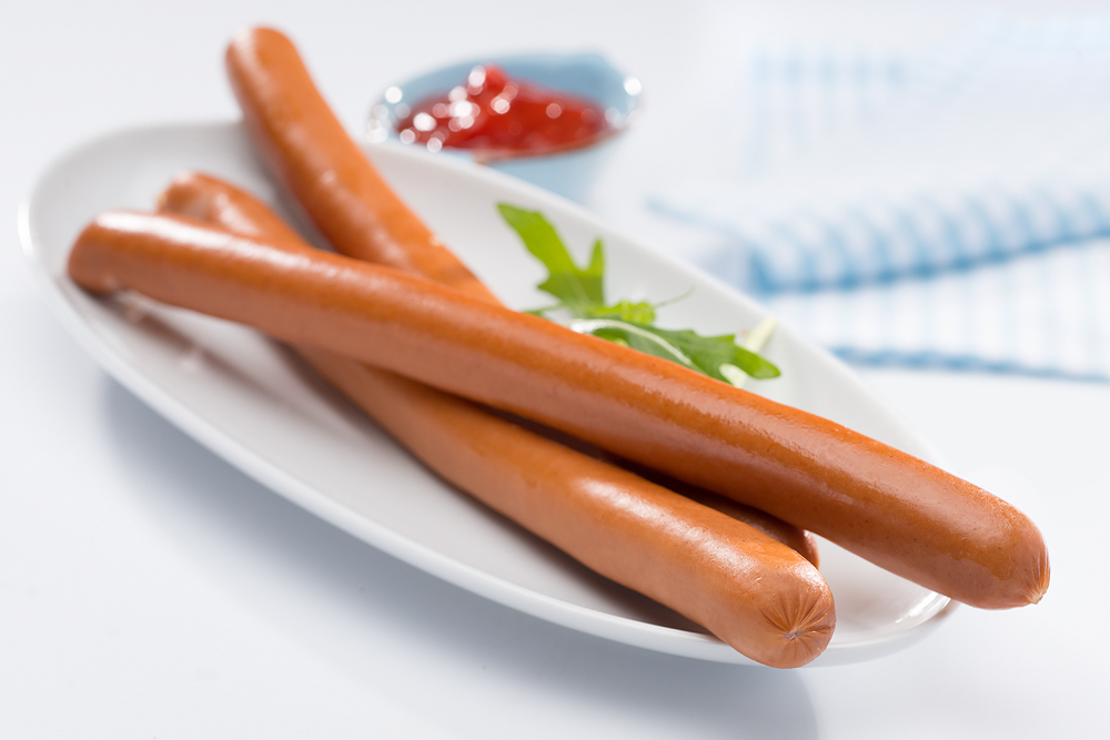 Drei lange Bockwürstchen auf einem Teller.
